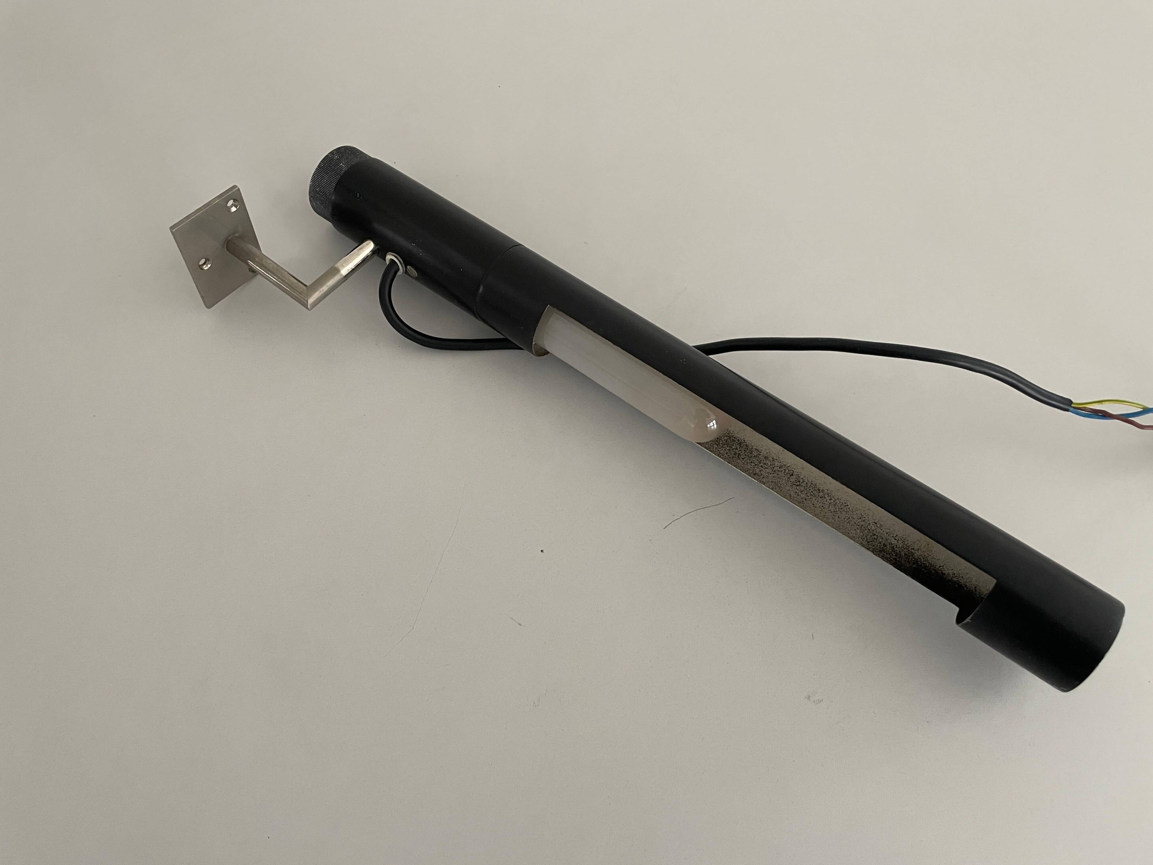 Minimalist black metal wall light with a cylindrical design, 1960s, Germany.