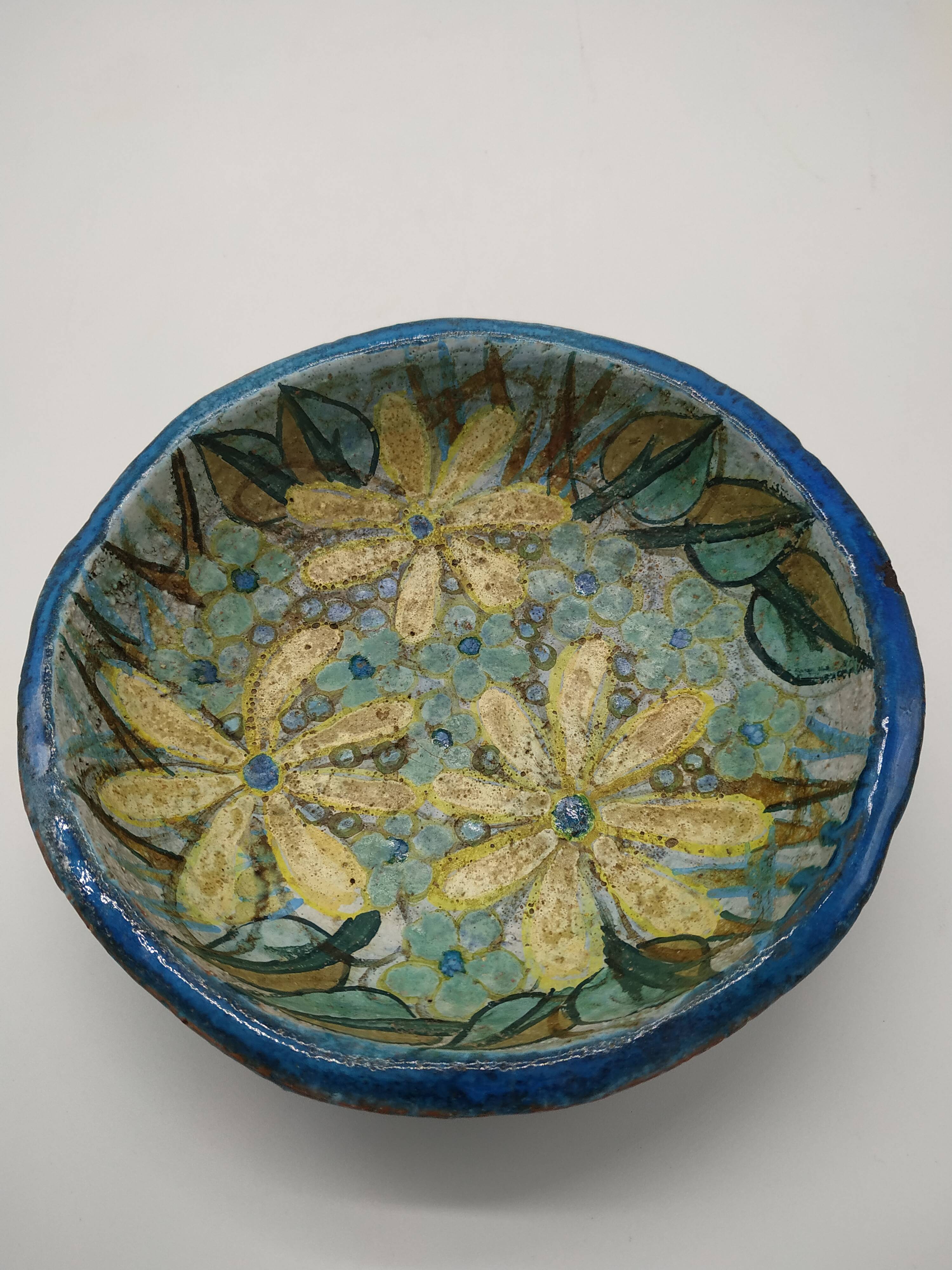 Hollow cut in blue enamelled sandstone decorated with yellow flowers