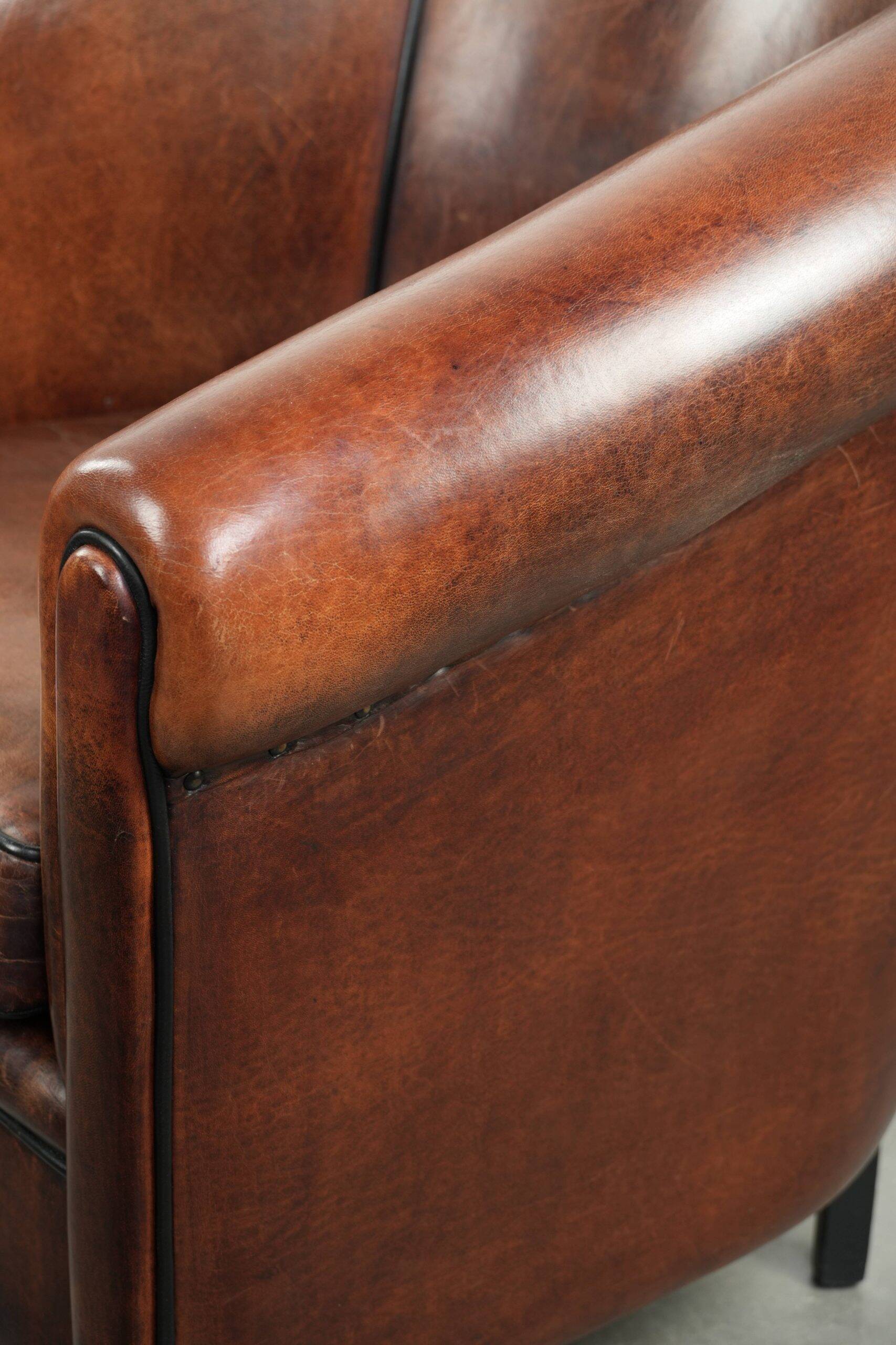 Sheepskin club armchair with deep warm colours and black piping