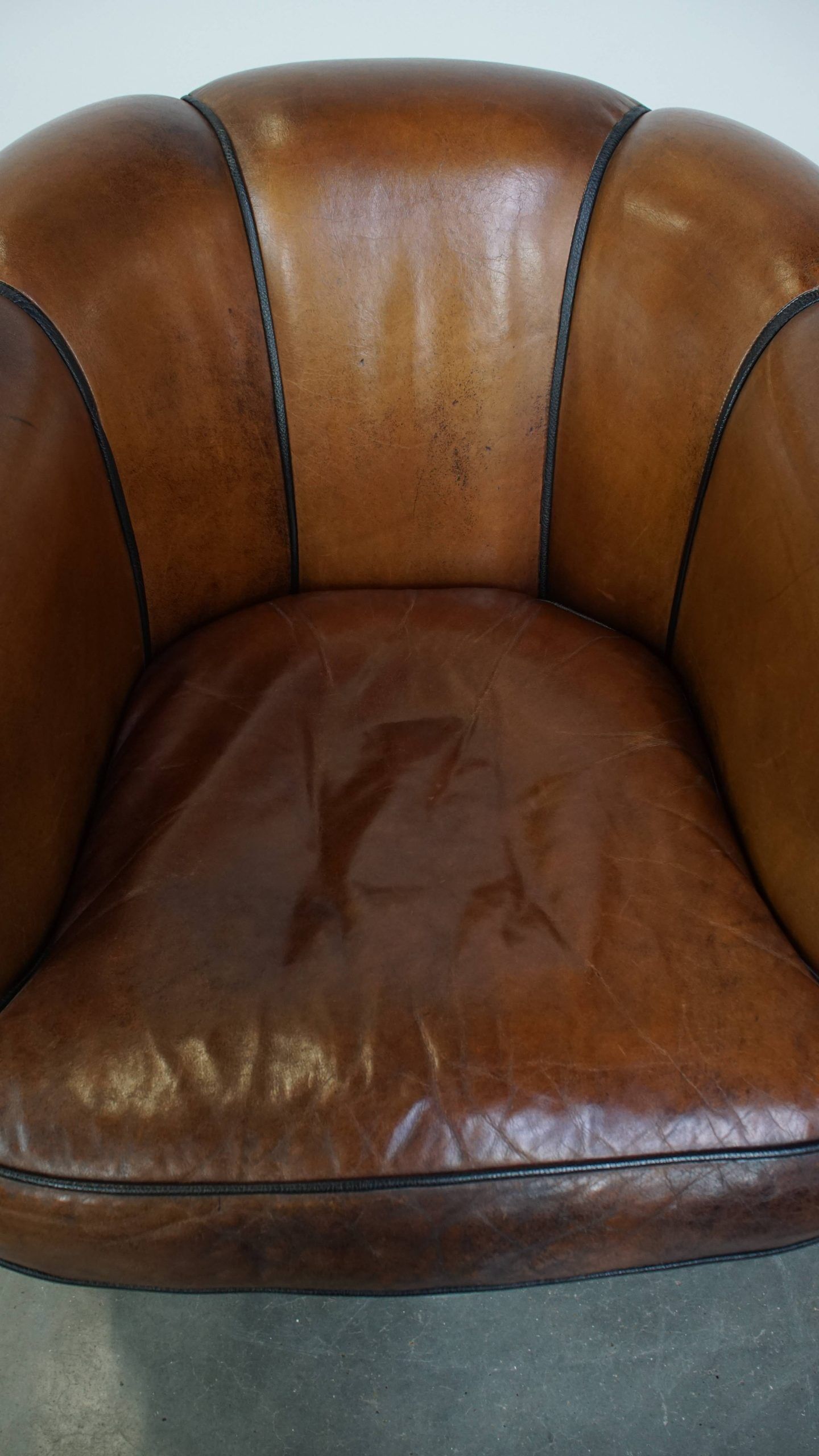 Unique vintage cognac-coloured leather club armchair with black piping