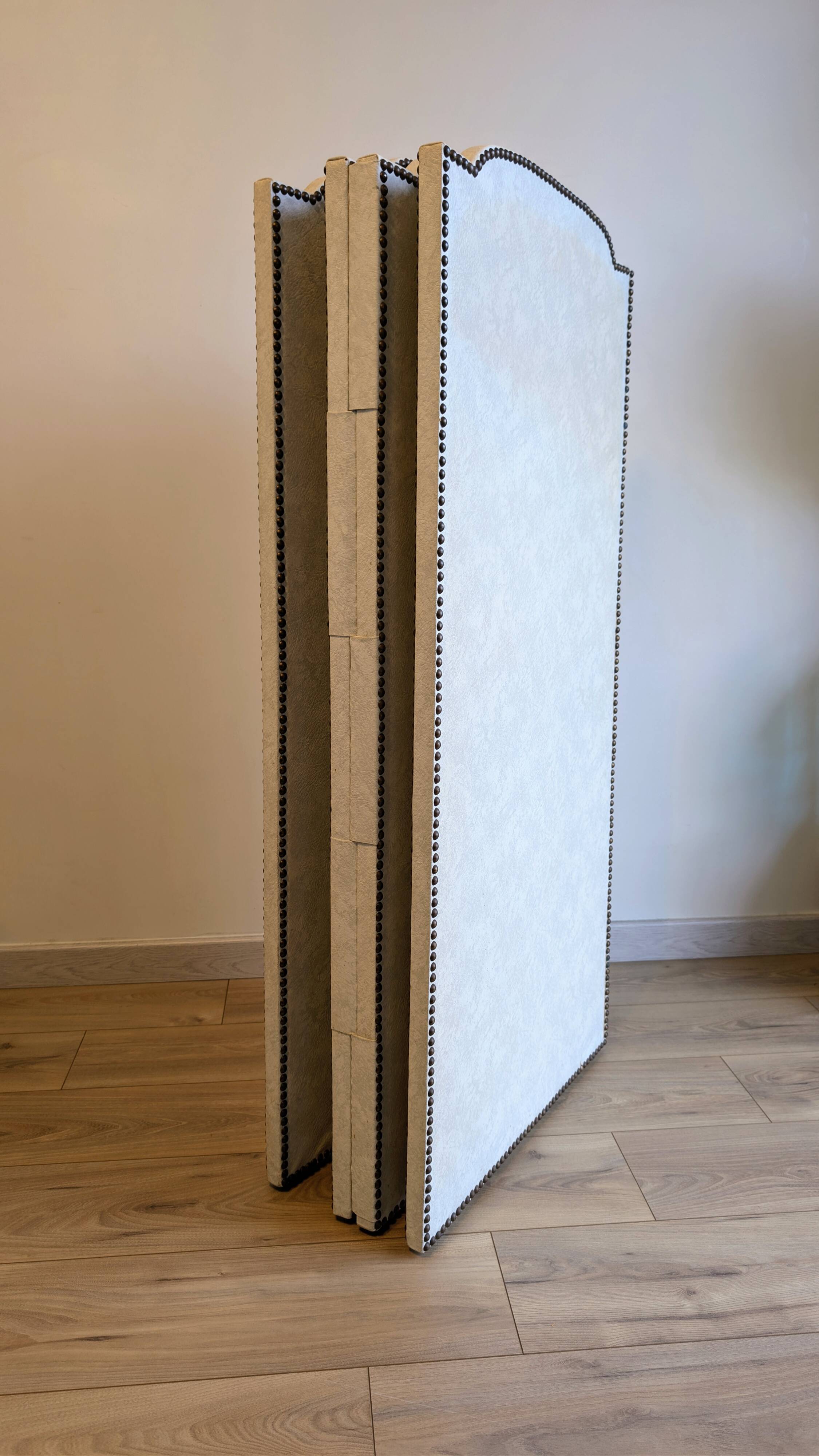 Vintage white faux leather screen with four studded panels, elegant decor.