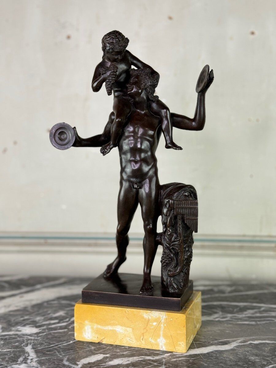 Dionysus on the shoulders of a satyr, bronze after the antique on a yellow Siena base.