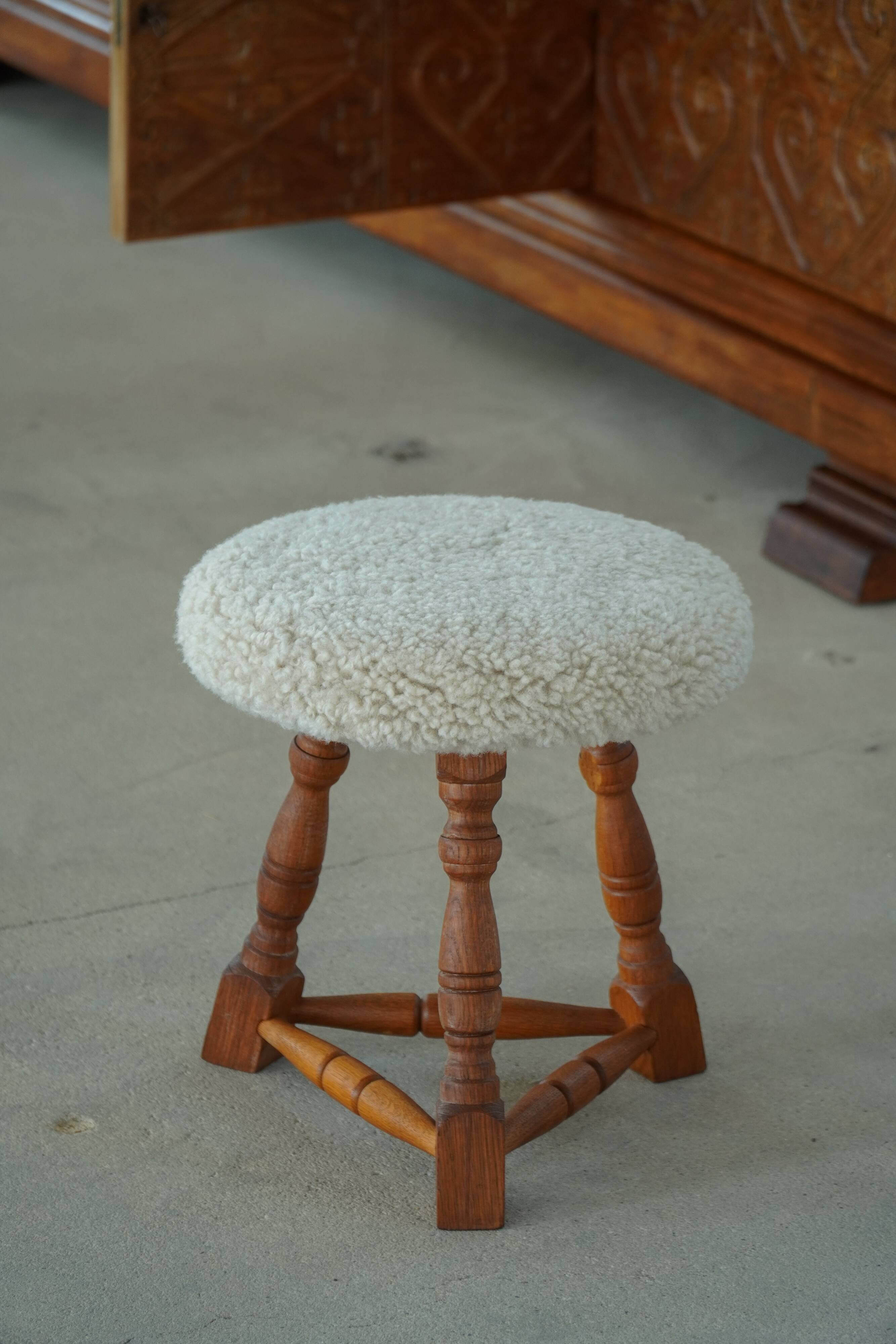 Modern Danish stool, with three oak legs featuring turned feet and a lambswool seat, 1950s.