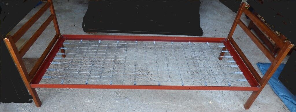 Single bed with wooden headboard and footboard and metal box spring