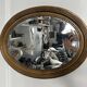 Antique oval mirror in gilded wood, bevelled mercury glass, 19th century.