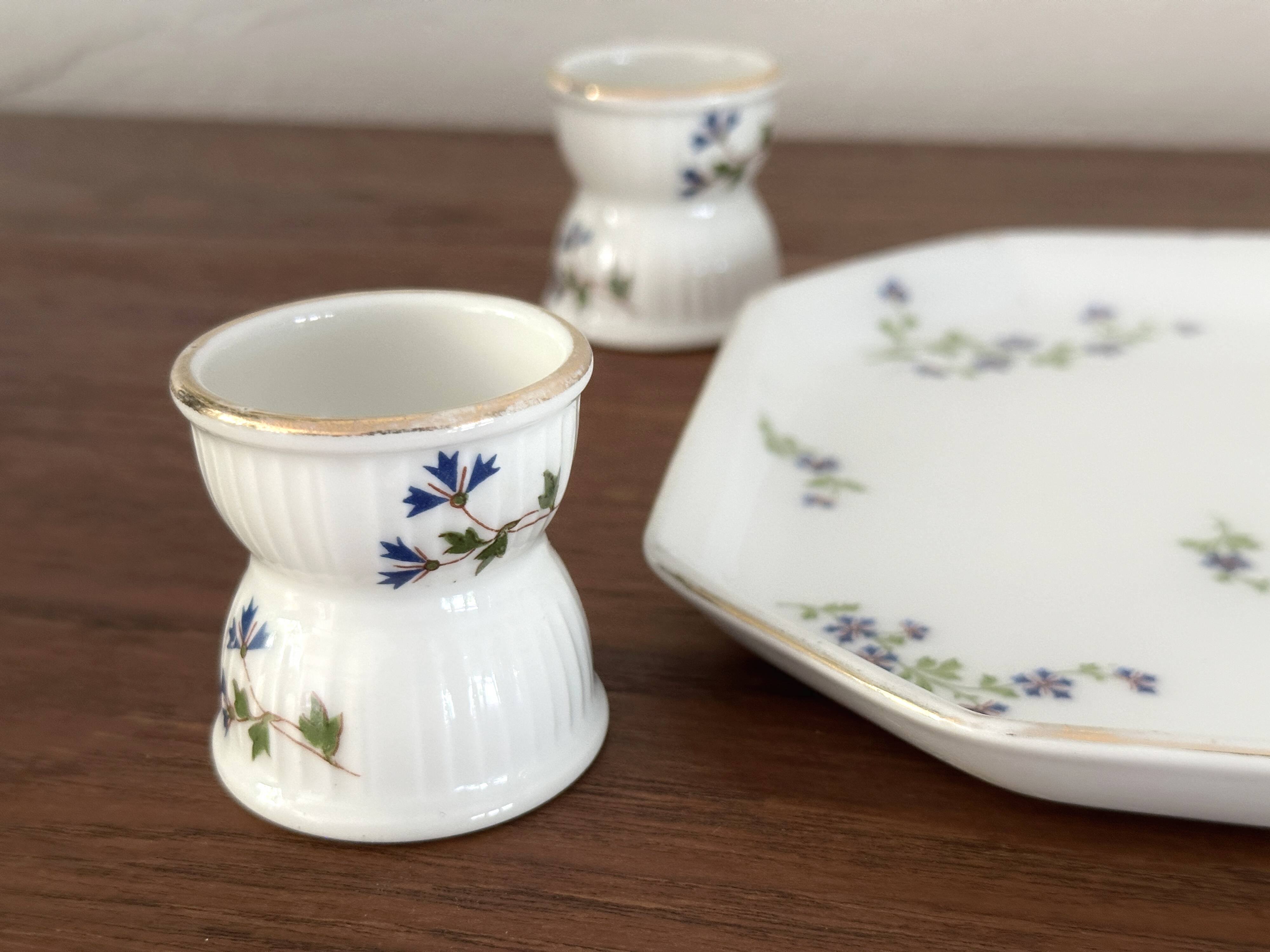 Egg cups on a Limoges porcelain tray by Bernardaud with a barbel decoration.