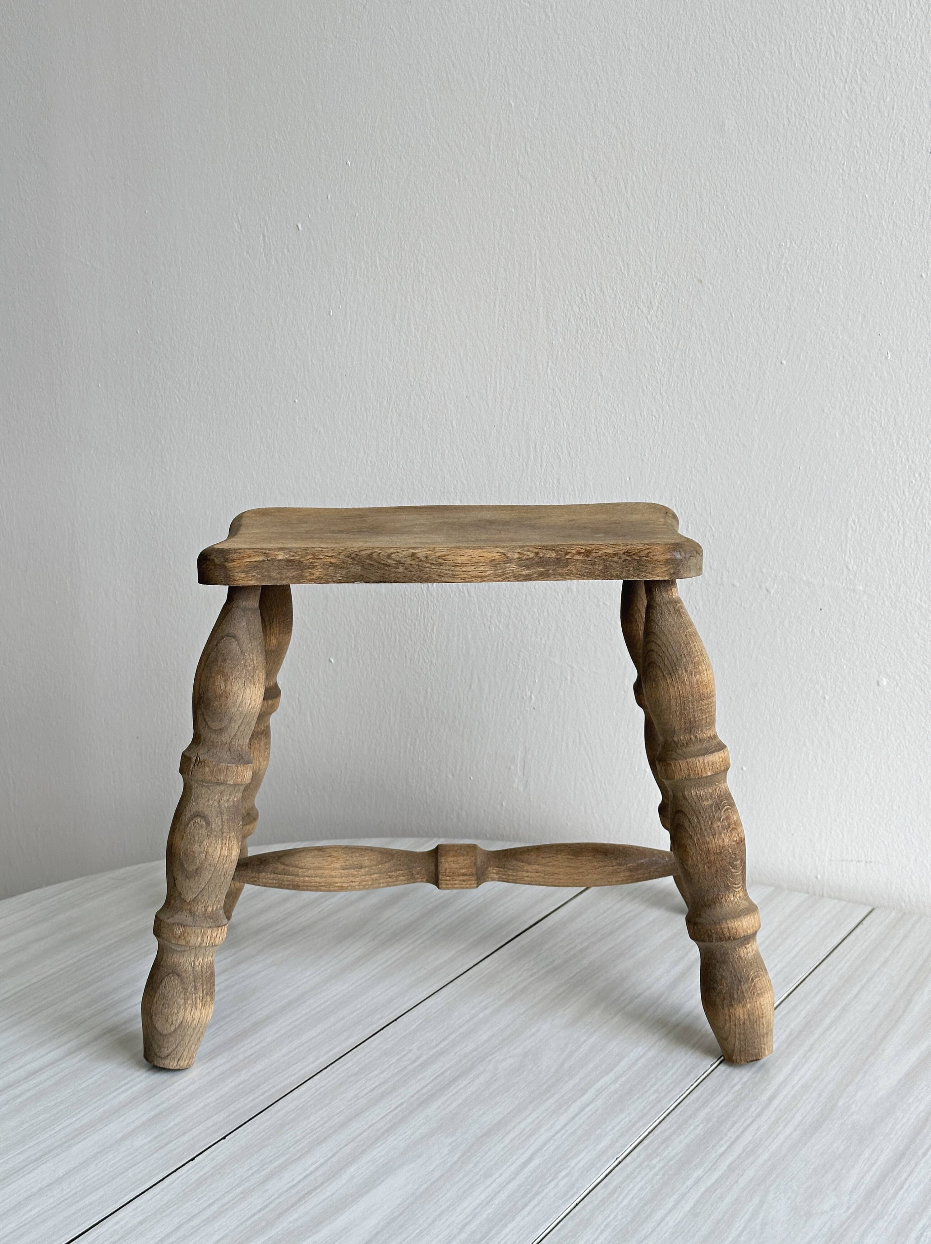 Antique wooden stool with four turned legs.