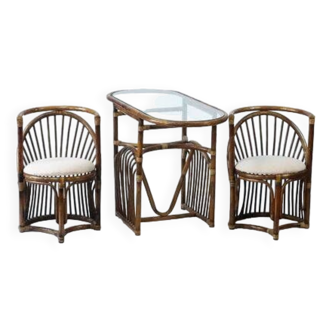 Table de jardin en bambou avec un plateau en verre et ses deux fauteuils.