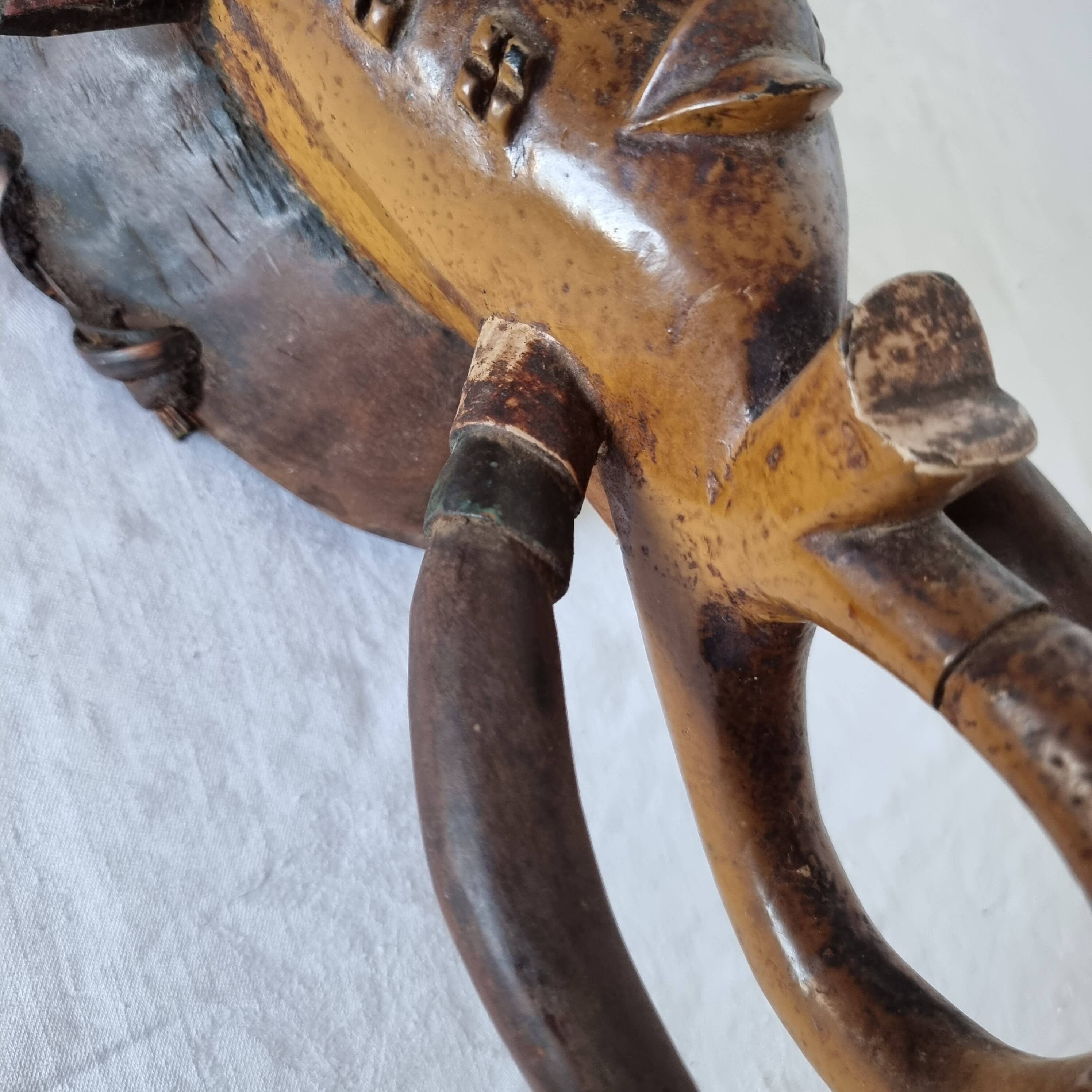 A large Senufo mask made of colored wood, decorated with an anthropomorphic figure