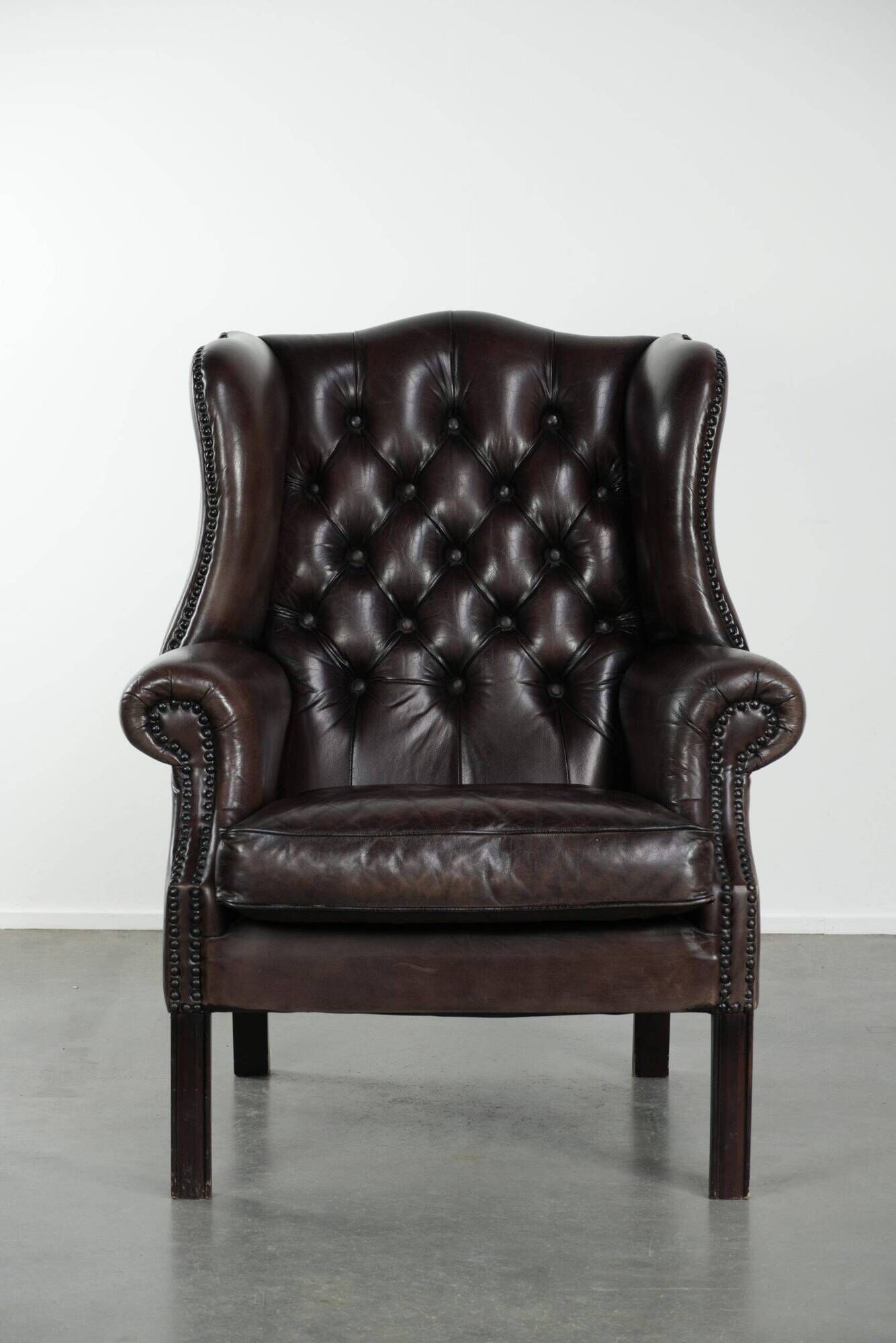 Dark brown cowhide Chesterfield wingback armchair in classic English style