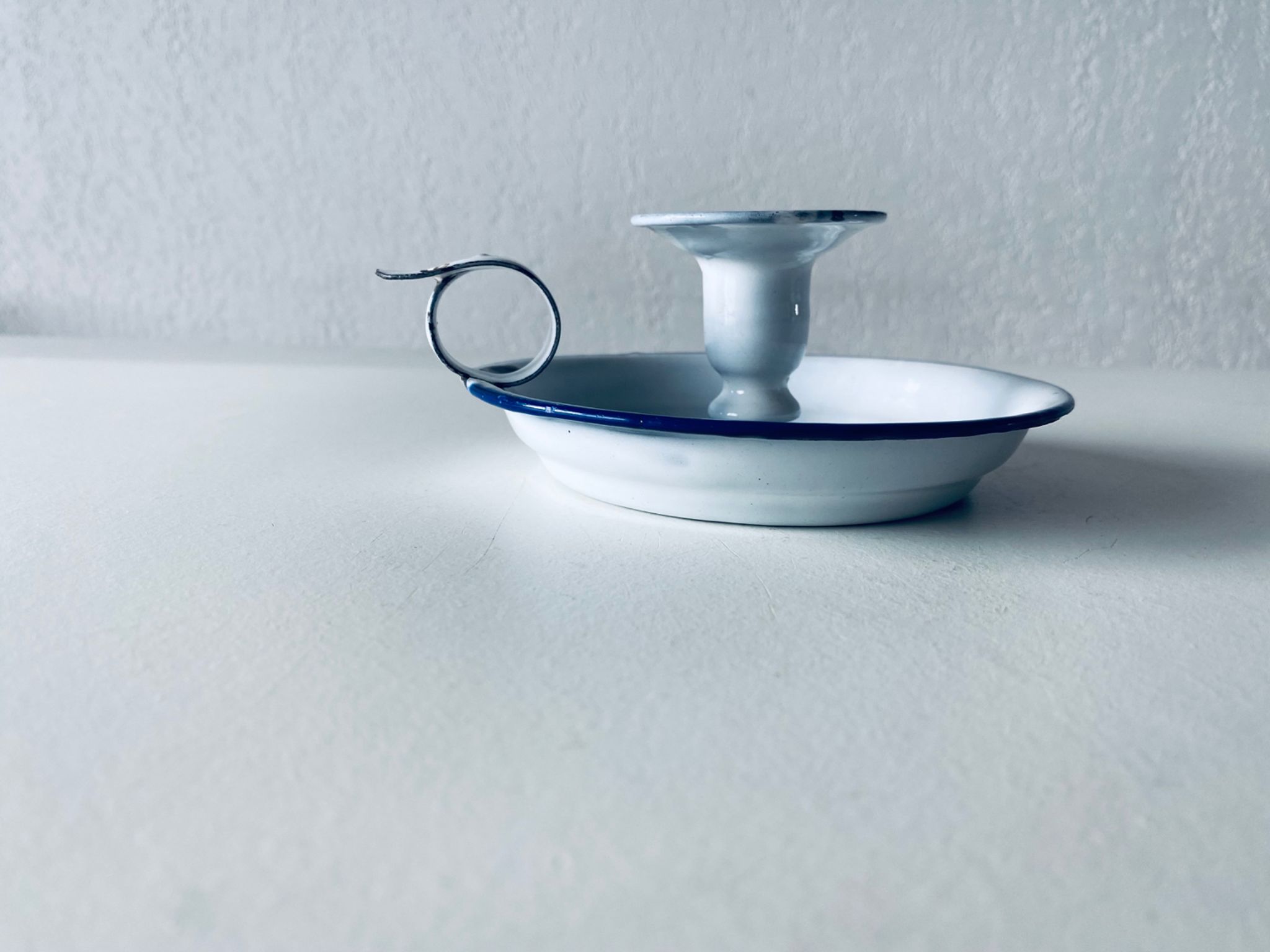 Old candle holder in white enameled metal