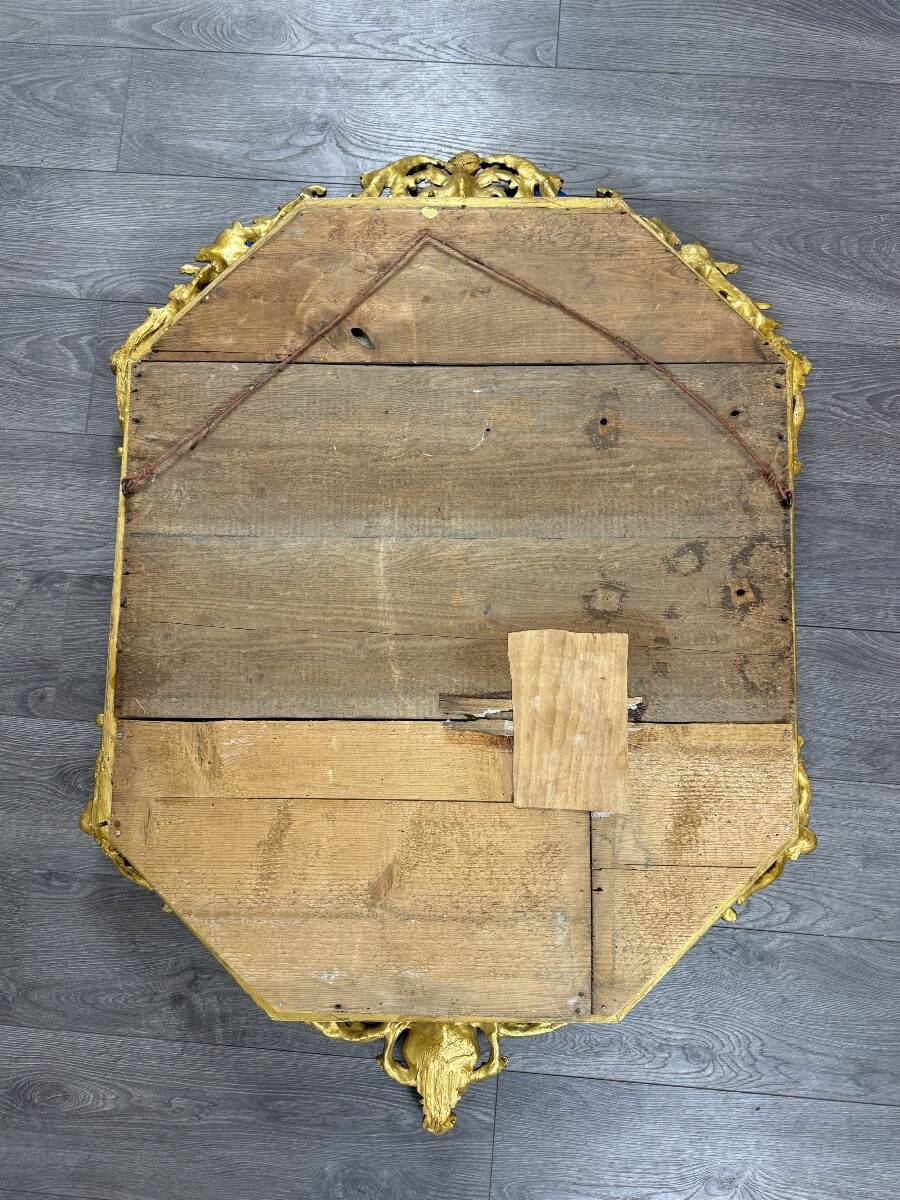 Antique octagonal mirror in richly carved gilded wood, Louis XV style.