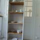 Shallow depth bookcase re-enchanted in pearl gray, wooden shelves.