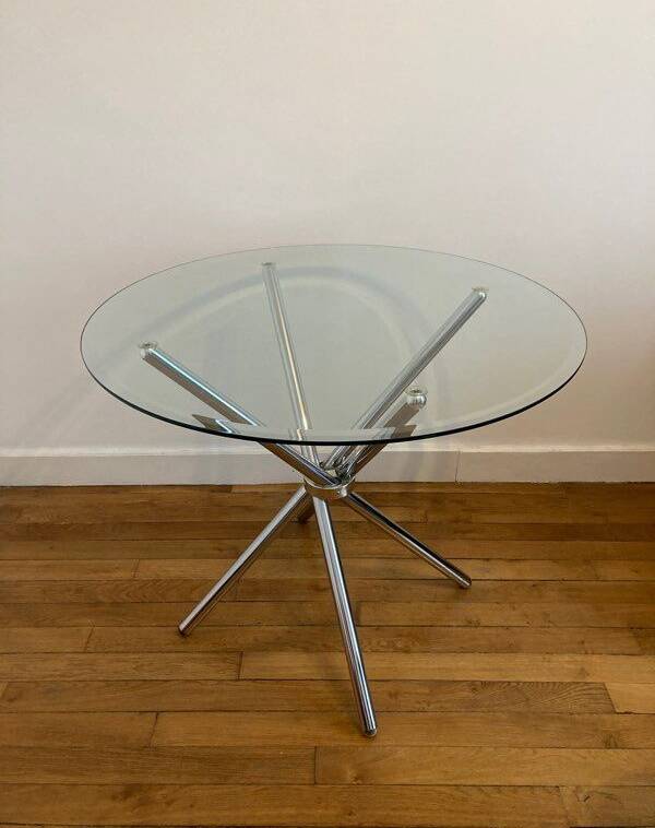 Round glass dining table with a chrome central base.