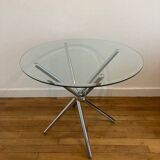 Round glass dining table with a chrome central base.