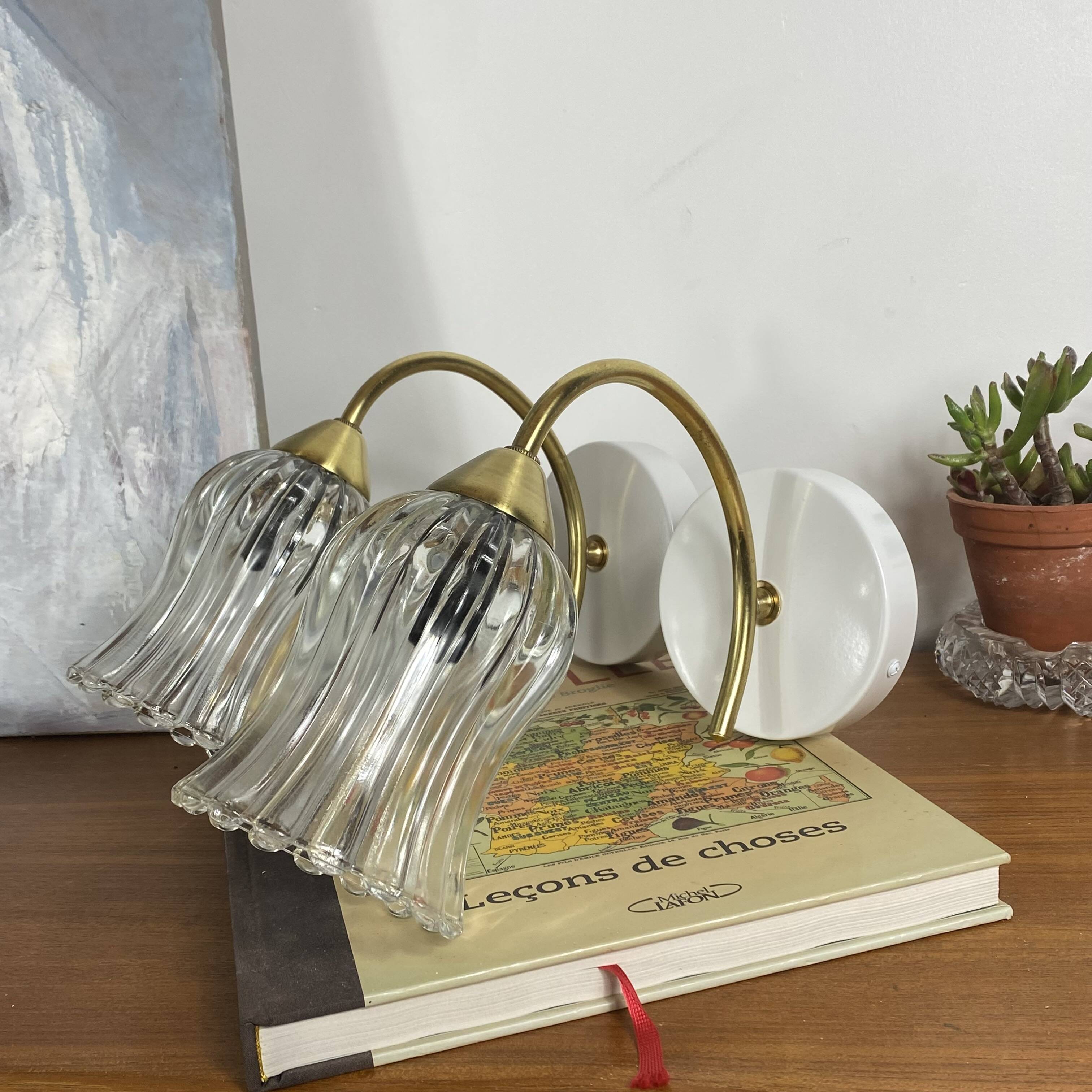 Pair of wall sconces in brass with transparent tulip glass shade.