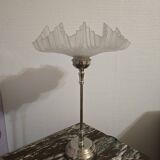 Table lamp with a silver base and a scalloped shade.
