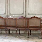 Grande banquette Louis XV en bois naturel mouluré et sculpté, France XVIIIème siècle