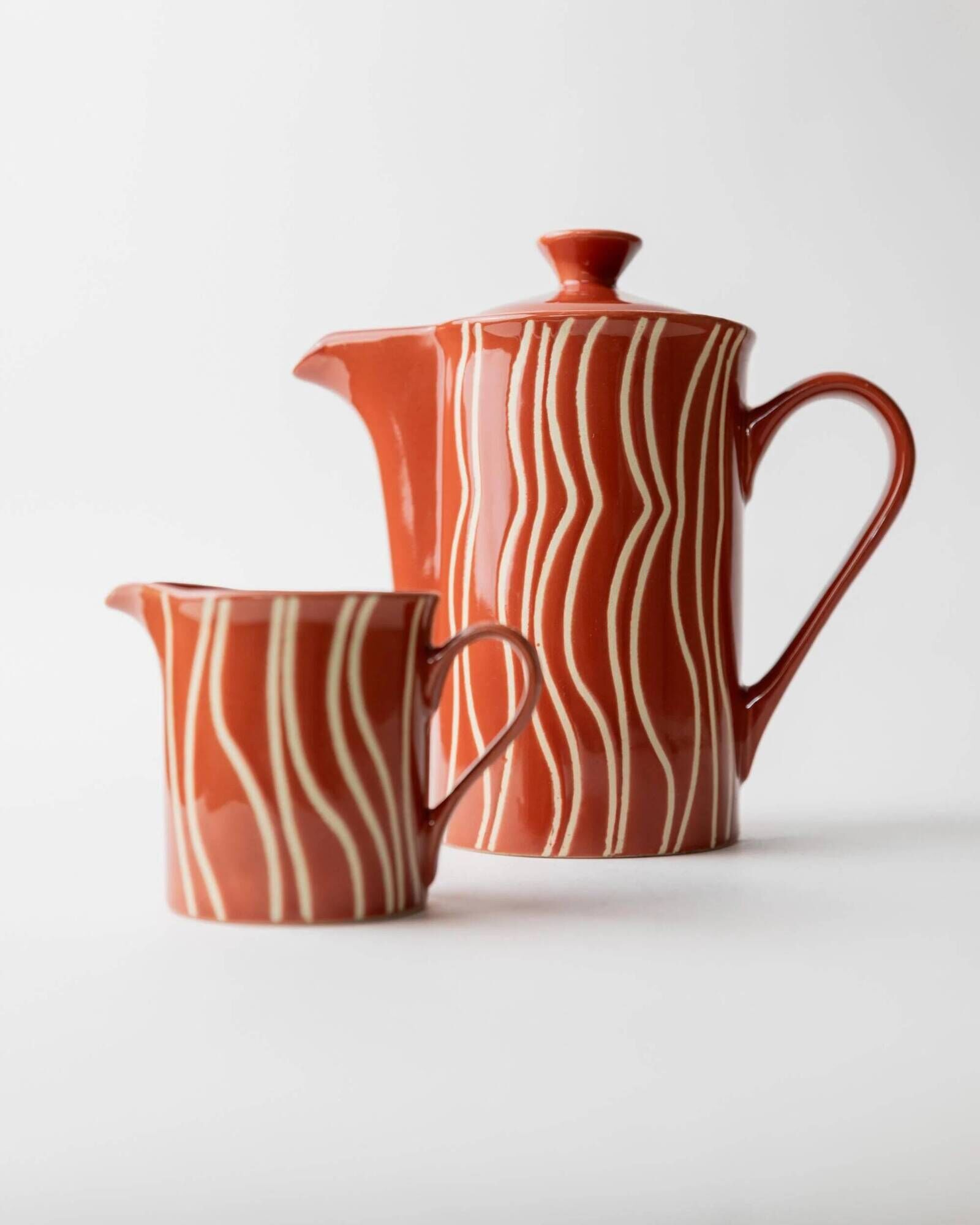 Vintage tea or coffee service in 1970s ceramic, teapot with lid and milk jug, rust orange with retro striped pattern, mid-century decoration, gift idea.