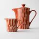 Vintage tea or coffee service in 1970s ceramic, teapot with lid and milk jug, rust orange with retro striped pattern, mid-century decoration, gift idea.
