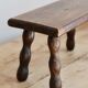 Vintage rectangular stool in dark wood with turned legs.