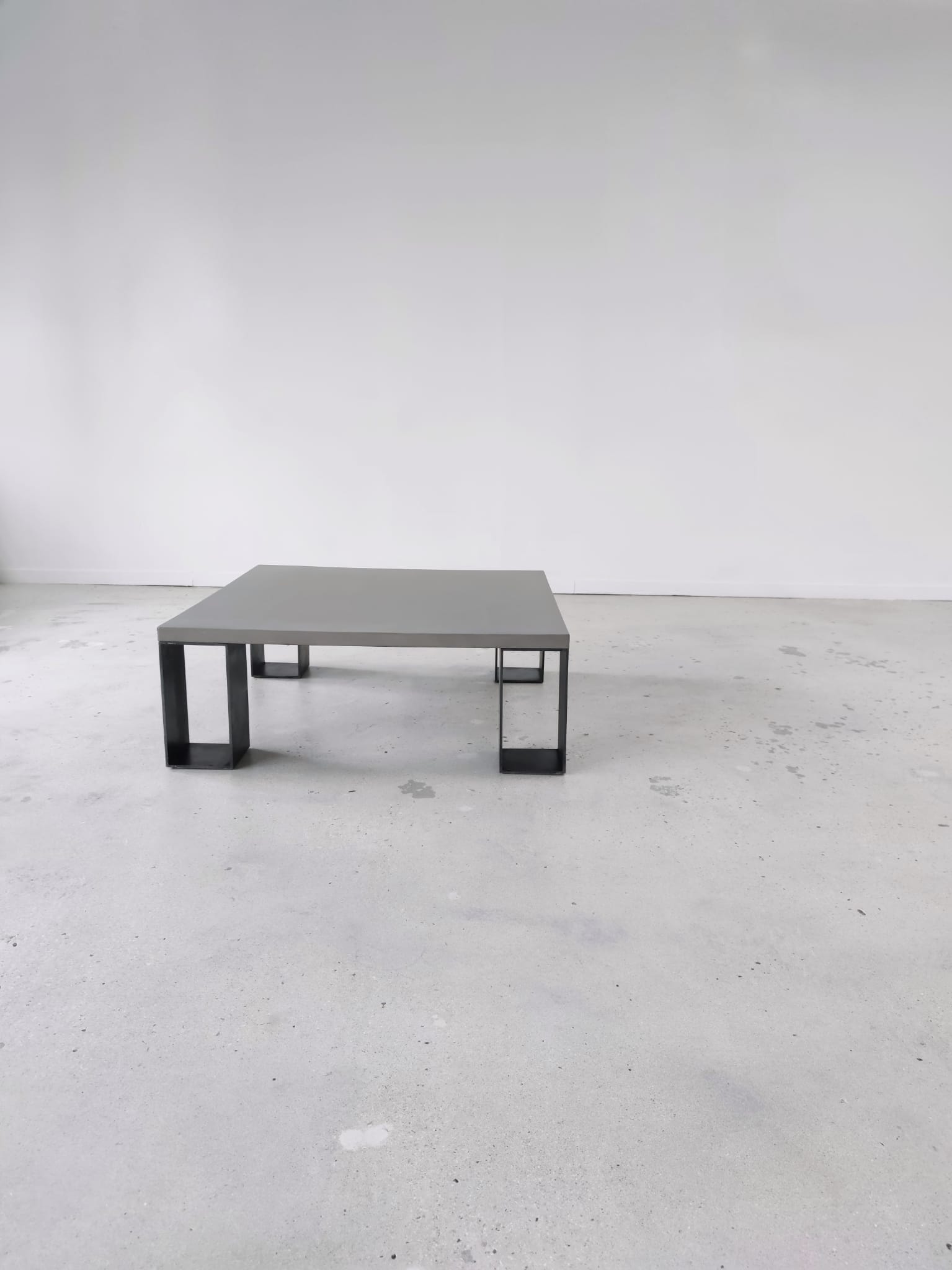 Table basse minimaliste en béton ciré et acier massif 1m20x1m20