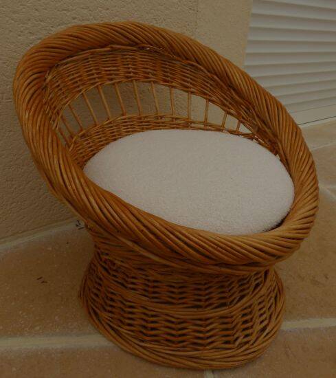 Wicker armchair with a high back and its boucle fabric cushion.