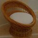 Wicker armchair with a high back and its boucle fabric cushion.