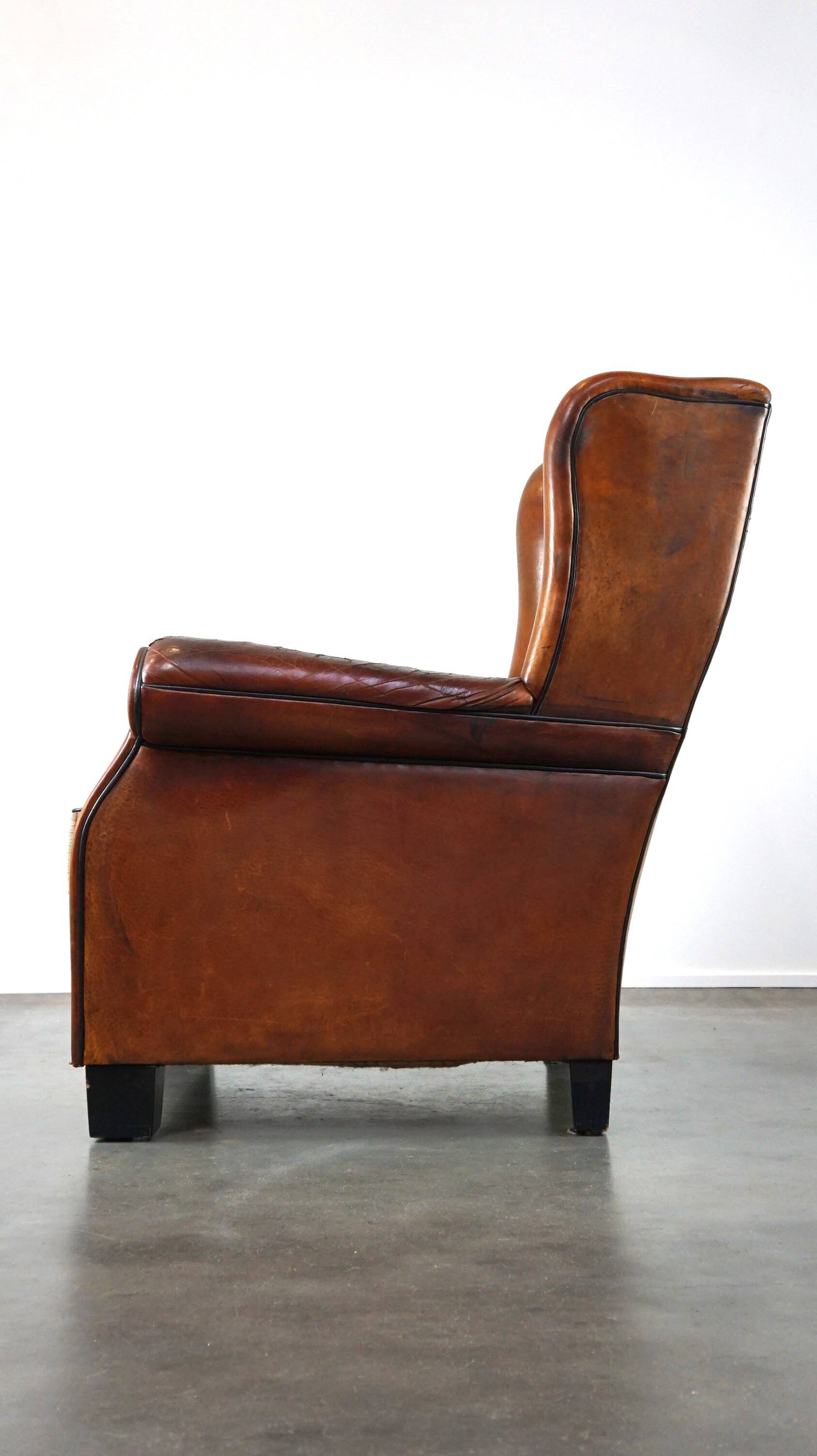 Very large worn sheepskin wing chair with a checked seat cushion