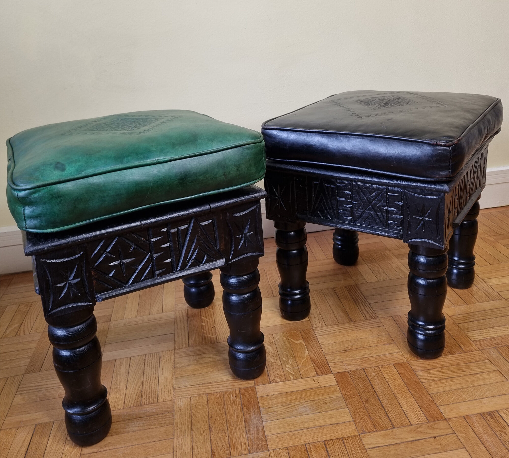 Pair of Moroccan poufs in stamped leather with a carved wooden base, Rabat