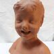 Terracotta bust of a smiling little boy.
