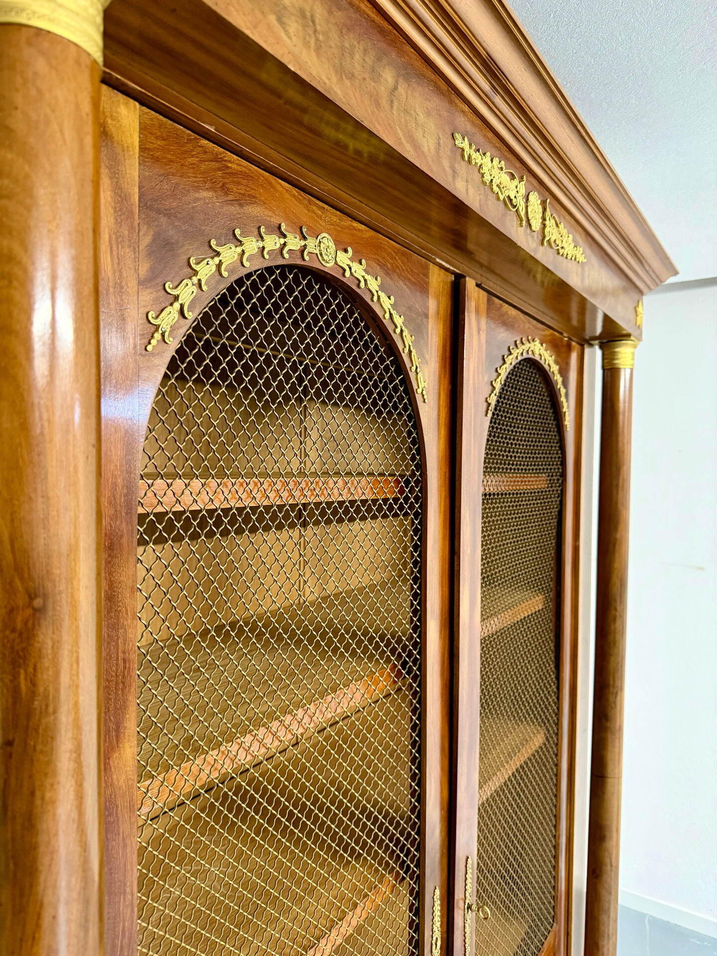 Large Empire-style library in wood with gilded bronze ornaments.