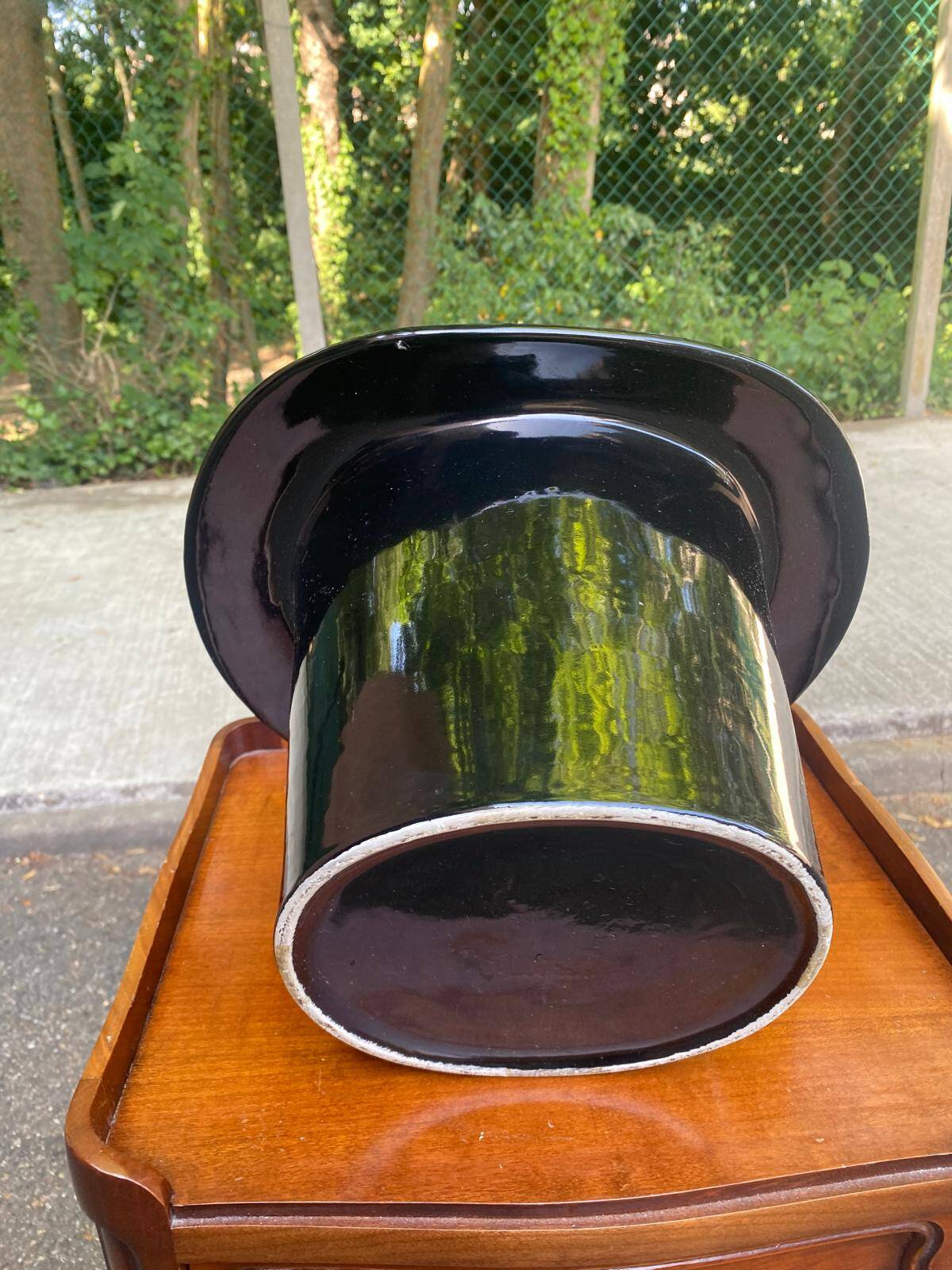 A black top hat-shaped vale turned upside down from the 1960s.