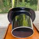 A black top hat-shaped vale turned upside down from the 1960s.