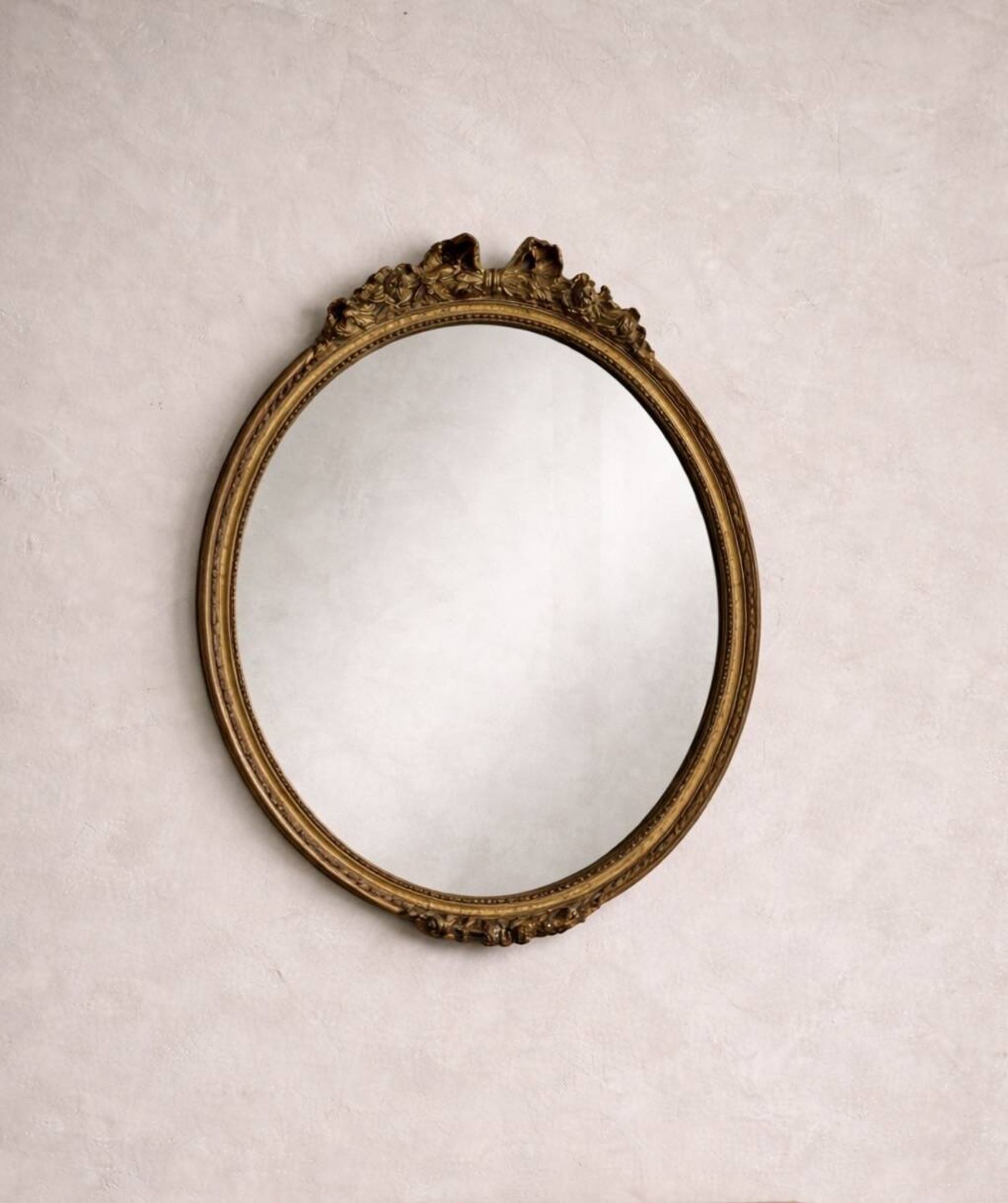 Antique oval mirror in Louis XVI style, gilded, with a bow pediment, 55cm.