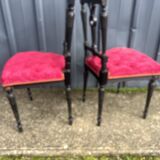 Pair of black lacquered chairs with purple tufted upholstery.