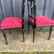 Pair of black lacquered chairs with purple tufted upholstery.