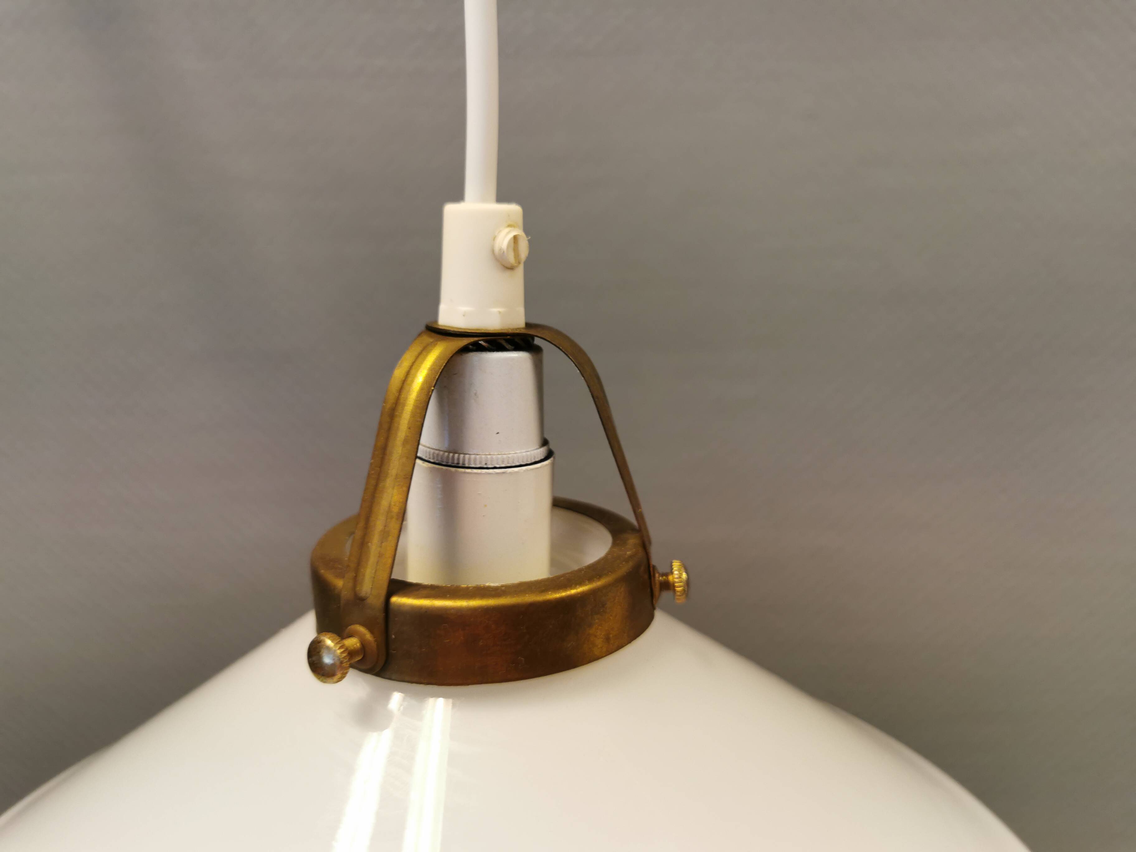 A set of hanging lamps in milky white opal glass with brass top.