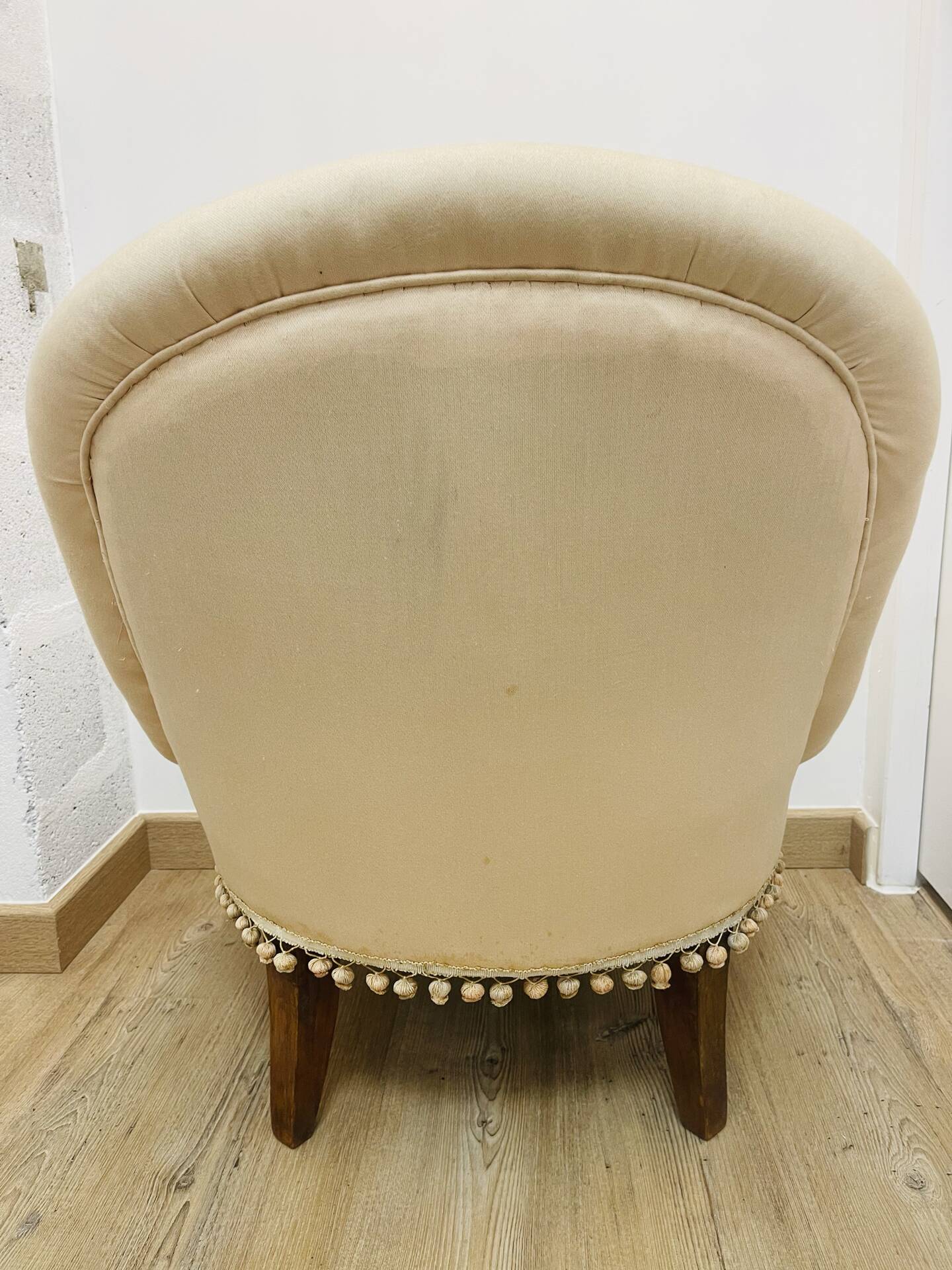 Pale pink upholstered armchair with wooden legs.