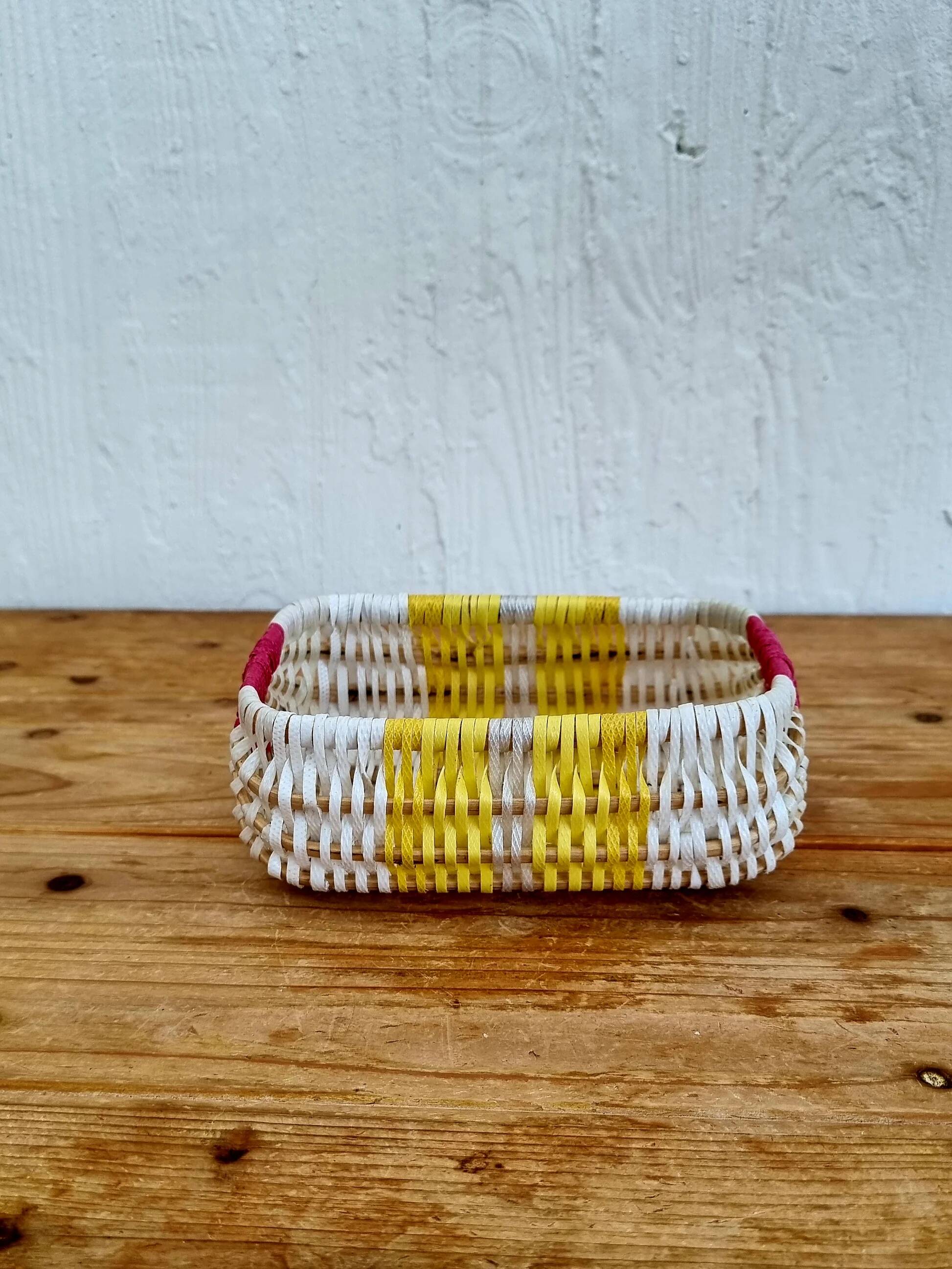 Vintage woven basket in yellow, white, and pink plastic.