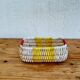 Vintage woven basket in yellow, white, and pink plastic.