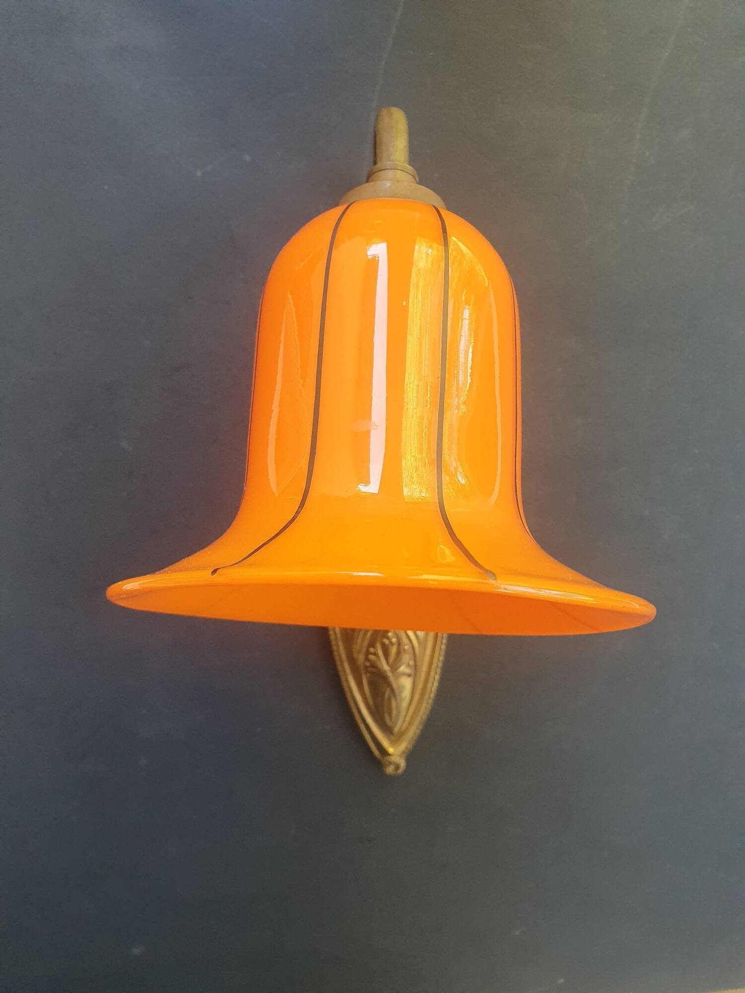 Art Deco wall light in brass with an orange globe.
