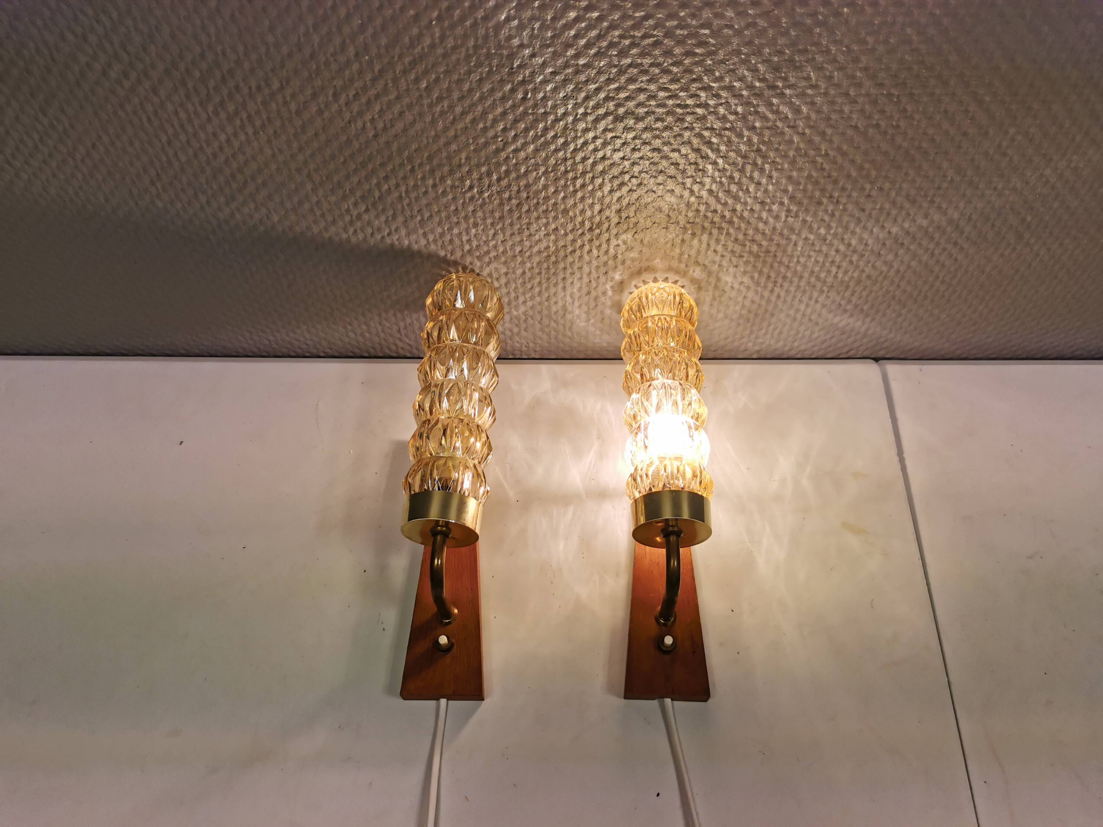 A set of Danish wall lights in champagne coloured glass with brass and teak.