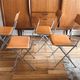4 folding Sintesi chairs for DWR Lina in metal and vintage camel leather.