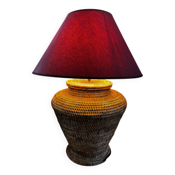 Woven rattan table lamp with a burgundy shade.