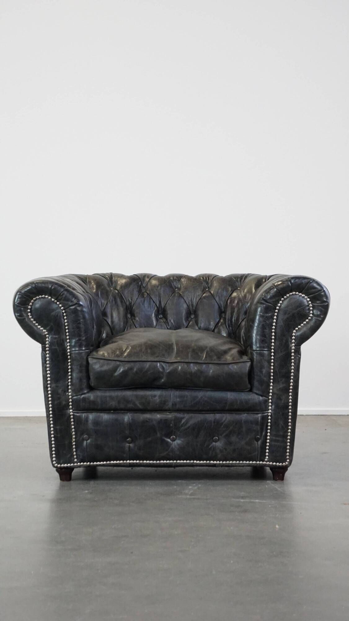 Spacious black cow leather chesterfield armchair with distinctive character