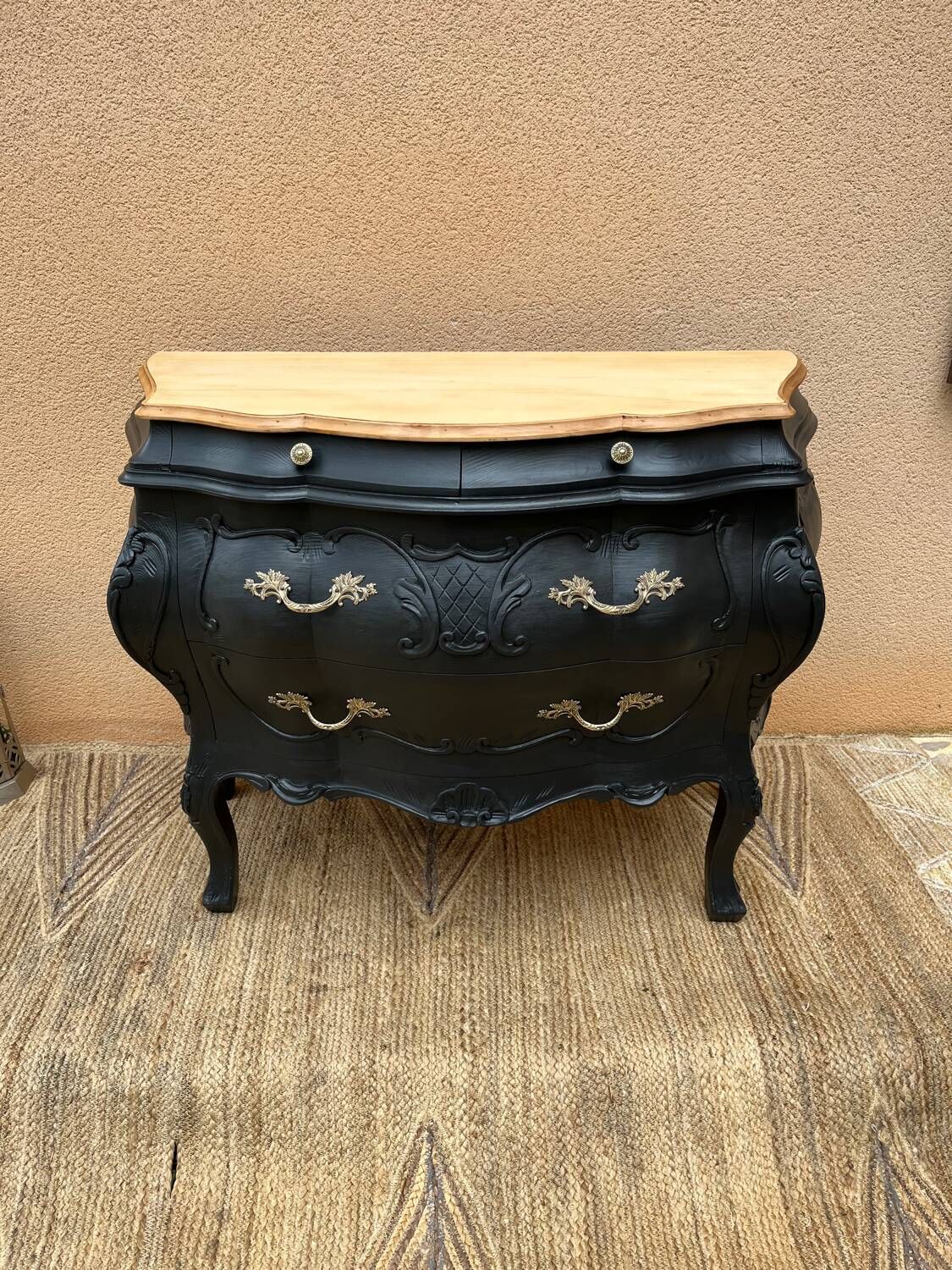 Curved commode painted in black and wood.