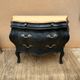 Curved commode painted in black and wood.