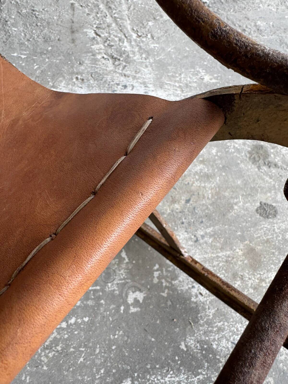 19th-century dark brown wrought-metal rocking chair with cognac leather sling seat, vintage