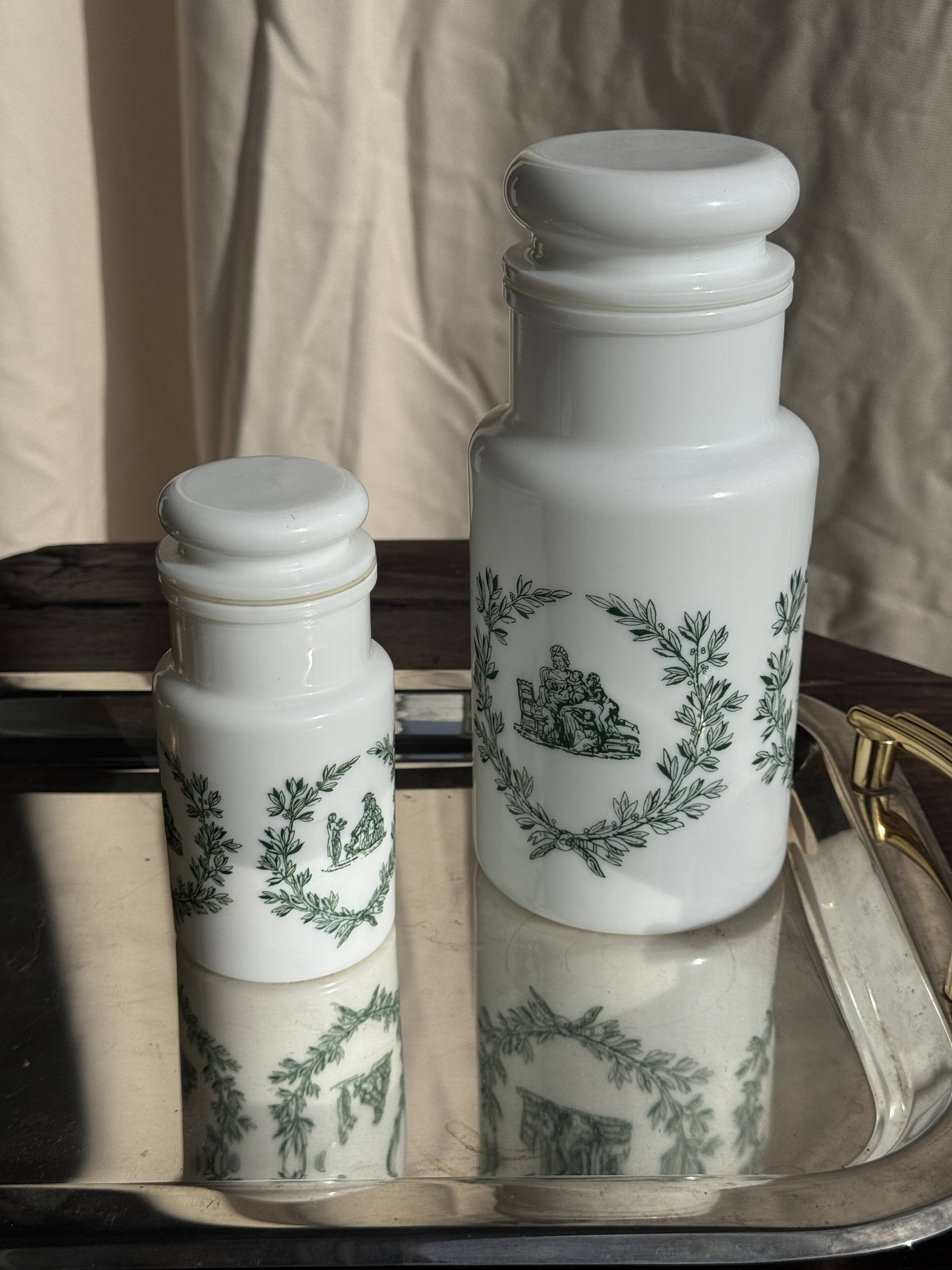 A pair of white glass bottles with Italian green patterns.